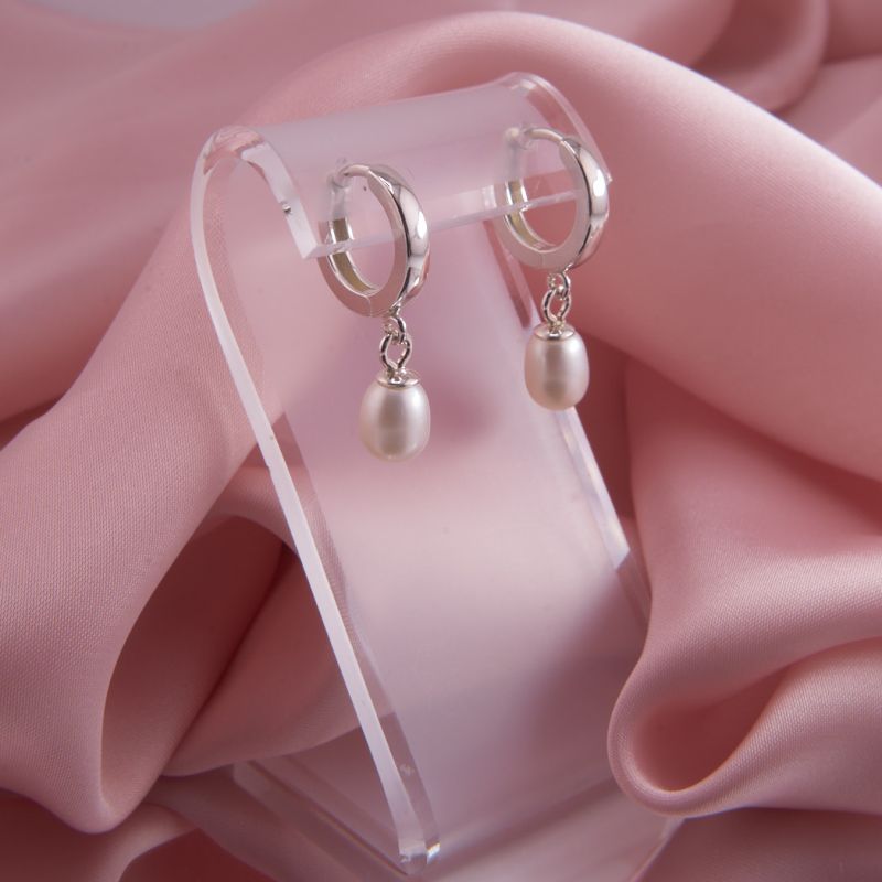 Silberne Creolen mit weißen Tropfen Perlen hängend präsentiert, um das sanfte Mitschwingen und das kühle Silber-Finish zu zeigen.